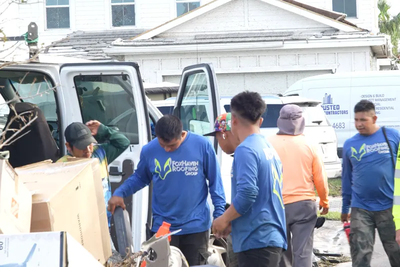 The crew loading debris into a van at the curb in Avenir after the storm