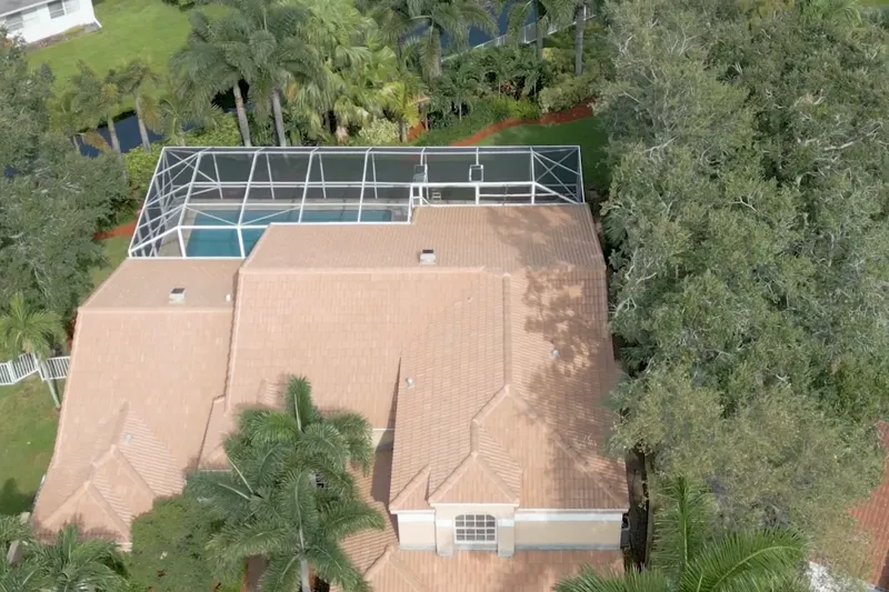 A drone view over a tile roof and screened pool in Siena Oaks, Palm Beach Gardens