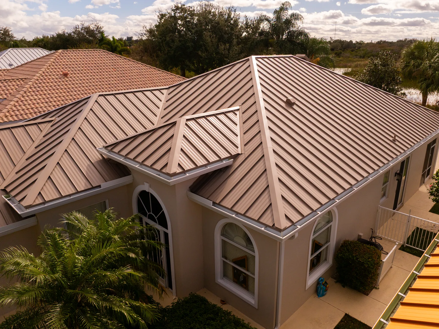 A bronze standing seam roof seen from above, its ridges running down to the gutters
