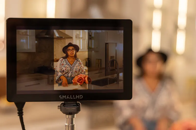 The field monitor on our camera framing a designer at her kitchen island, lights set around the room