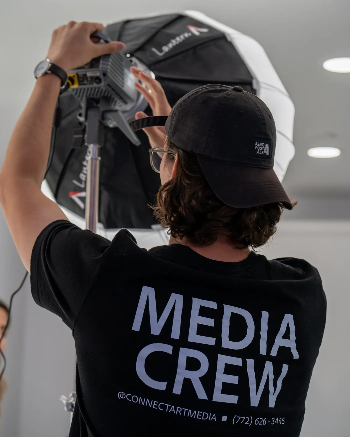 One of our crew setting up a light on set, wearing a Media Crew shirt