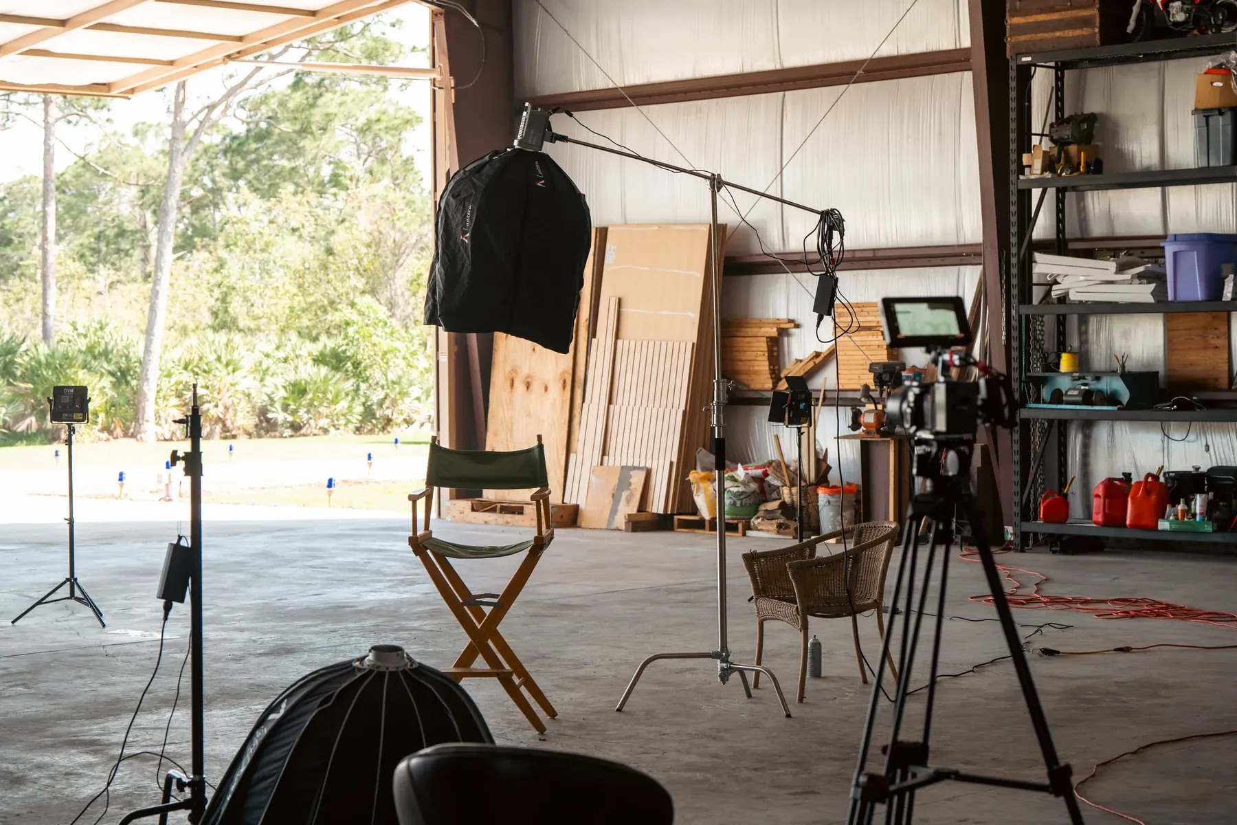 Lights, a camera and a director's chair set up inside an open warehouse