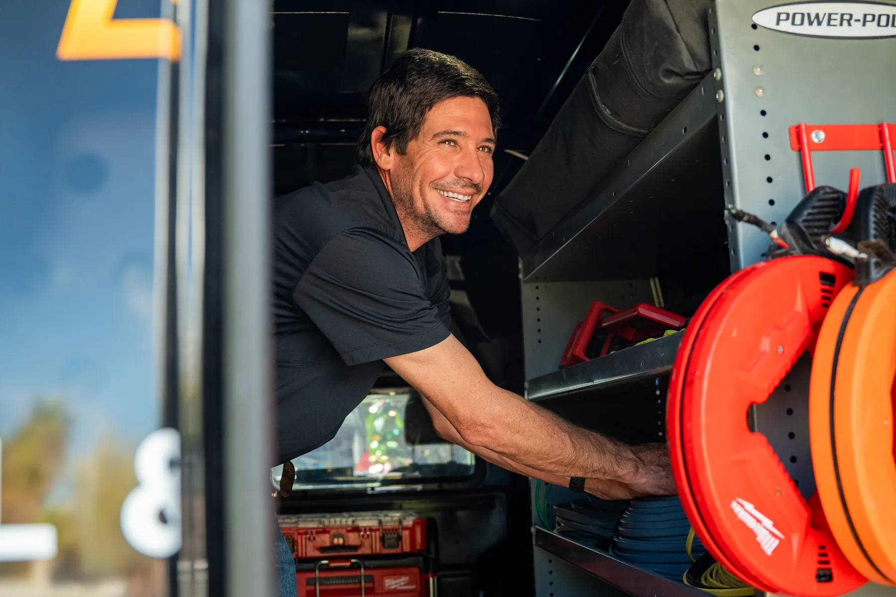 An electrician pulling a cable reel out of the van