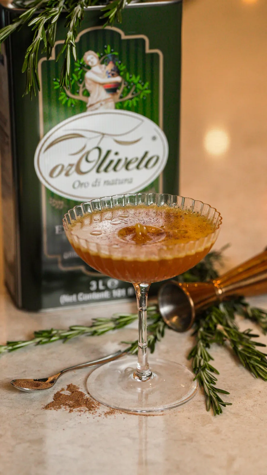 A cocktail in a coupe with rosemary