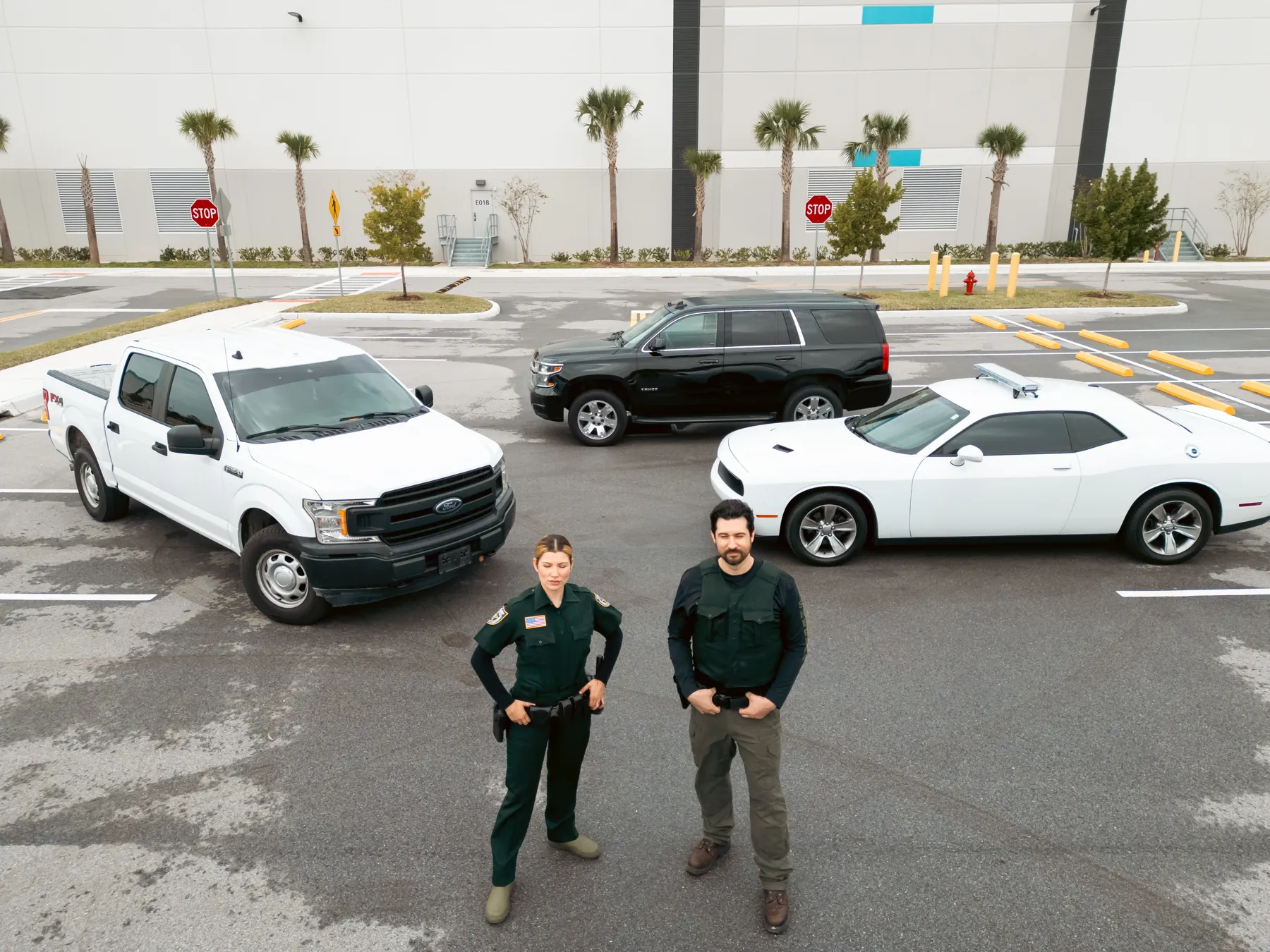 Drone view of a deputy and an officer standing in a parking lot between a white pickup, a black SUV and a white car