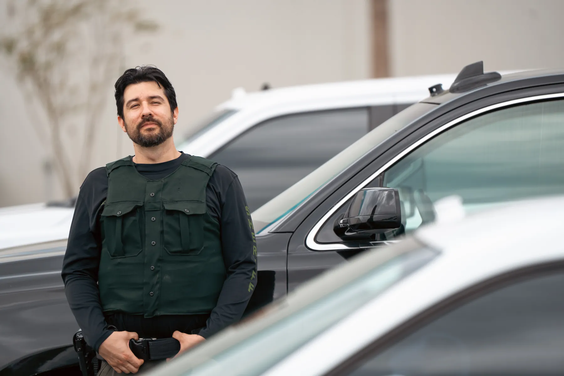 An officer in a dark uniform standing beside a parked car