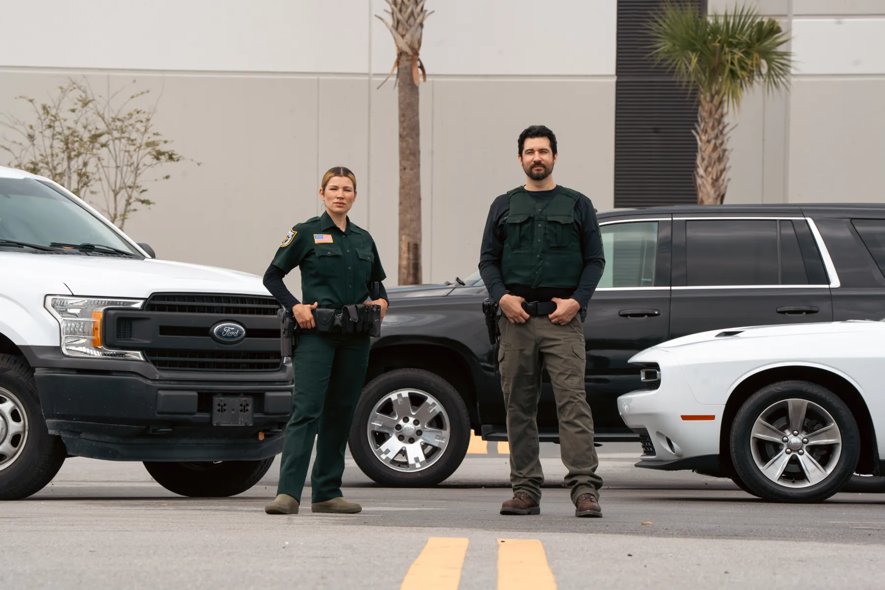 A deputy and an officer standing side by side in front of their vehicles